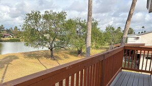 Eine Holzterrasse mit Blick auf einen See und Bäume.