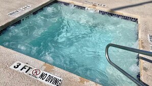Ein Schwimmbecken mit einem Schild, das vor dem Sprung warnt, und einer Metallleiter.