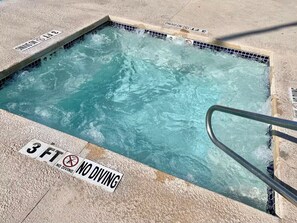 Ein Schwimmbecken mit einem Schild, das vor dem Sprung warnt, und einer Metallleiter.