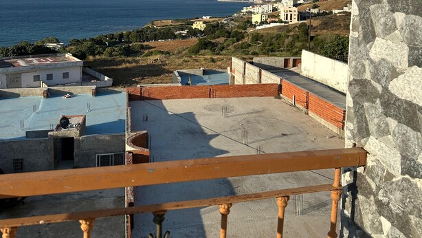 Ένα μπαλκόνι με θέα στη θάλασσα και σε κτίρια που διακρίνονται στο βάθος.
