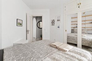 Een slaapkamer met een bed, een spiegel, een kledingkast en een deur naar een gang.