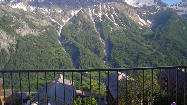 Un paysage de montagne avec une vallée et un bâtiment au premier plan.