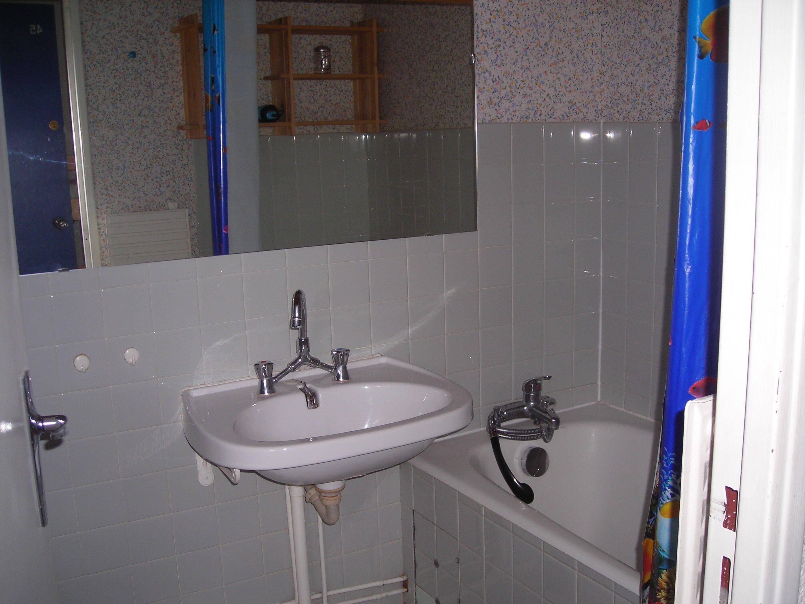 A bathroom with a white sink, a bathtub, and a mirror.