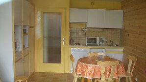 Une cuisine compacte équipée d’un four à micro-ondes, d’une machine à café et d’une petite table à manger avec des chaises.
