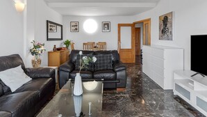 A modern living room with a black leather sofa, a glass coffee table, and a white cabinet.