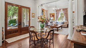 Un coin repas avec une table en verre, des chaises en bois, un vase de fleurs et une vue sur l’extérieur grâce à une porte vitrée.