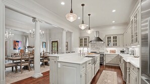 Une cuisine spacieuse avec des meubles blancs, un îlot central et des luminaires suspendus.