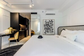 A hotel room with a bed, a desk, a chair, a hat on the bed, and a wall art piece. - One of a Kind Charlie Hotel Ibirapuera - Soft Opening (Sao Paulo)