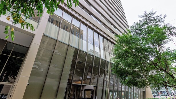 Un edificio moderno con amplios ventanales de vidrio, una entrada visible y un cartel.