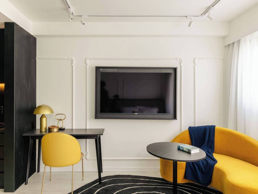 Una habitación moderna con un escritorio negro, una silla amarilla y un sofá amarillo.