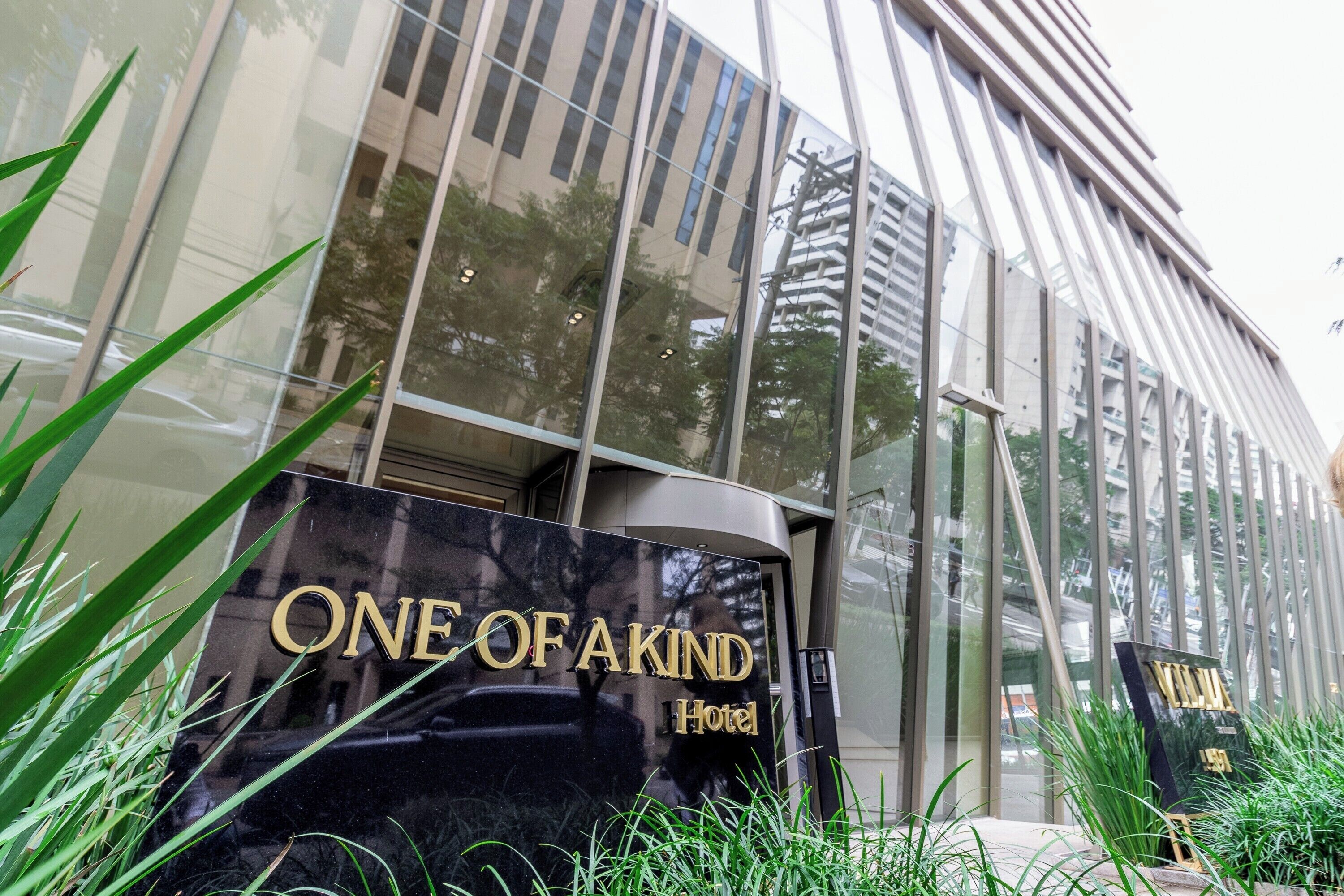 A modern building with a reflective glass facade and a sign that reads 'ONE OF A KIND Hotel.'