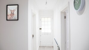 A hallway with a framed deer painting, a clock, and a door at the end. - 3BR Stays 10 Mins from Legoland/Ascot/Heathrow - Free Wi-Fi/Parking (Windsor)