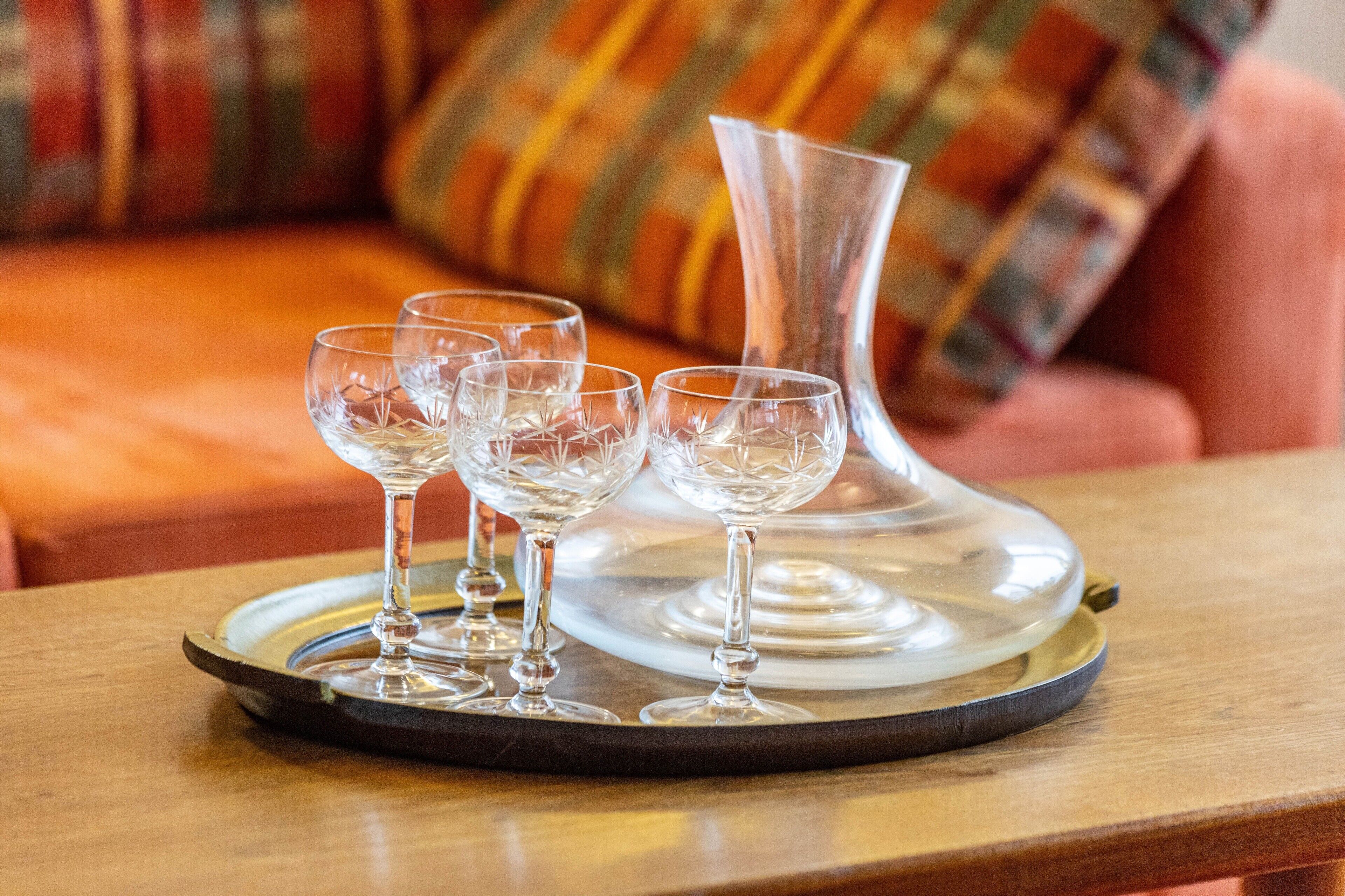 Un plateau avec quatre verres à vin et un vase transparent, posés sur une table en bois.