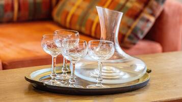 Un plateau avec quatre verres à vin et un vase transparent, posés sur une table en bois.