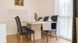 A dining area with a table set for two, two chairs, a decorative bird sculpture, and a framed picture on the wall. - Wycombe Oasis - Cozy 3-bed House Retreat (High Wycombe)