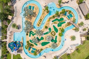 An aerial view of a resort with multiple swimming pools, a water slide, and sun loungers. - Gatsby Gamehouse (Kissimmee)