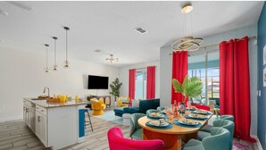 A modern kitchen with a central island, a dining area with a round table, and a living space with a sofa and chairs. - Gatsby Gamehouse (Kissimmee)