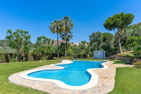 Ein Swimmingpool mit Steinrand, umgeben von einer gepflegten Rasenfläche und Bäumen.. Freistehendes Haus mit 3 Schlafzimmern und privatem Whirlpool, 15 Min. von Marbella entfernt