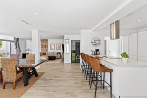 Une cuisine moderne avec un coin bar, une table à manger avec des chaises et un espace salon avec un canapé et un téléviseur.