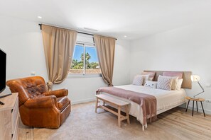 Ein Schlafzimmer mit Bett, Stuhl, Bank, Schreibtisch und Lampe.