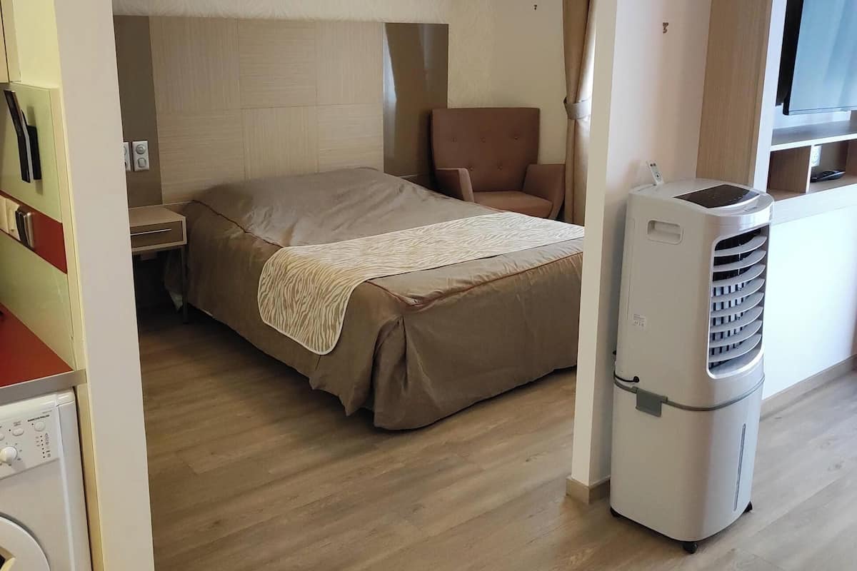 A hotel room with a bed, a chair, a TV, and a washing machine.
