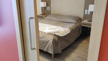 A hotel room with a bed, bedside tables, and a wooden floor.