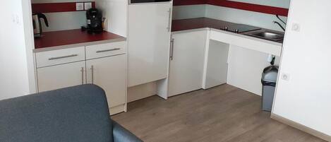 A compact kitchen with white cabinets, a built-in oven, and a red countertop.