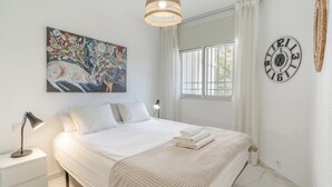 A bedroom with a bed, a painting, a clock, and a window. - Apartment in Los Pacos, Fuengirola (Fuengirola)