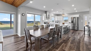 A modern kitchen with a large island, white cabinetry, and a view of the ocean.