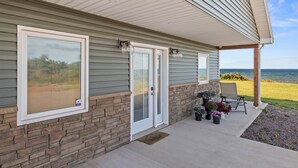A house with a covered porch, stone foundation, and a view of the ocean.