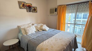 A bedroom with a bed, a small round table, and a window with curtains.