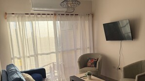 A living room with a sofa, armchairs, a coffee table, and a flat-screen TV mounted on the wall.