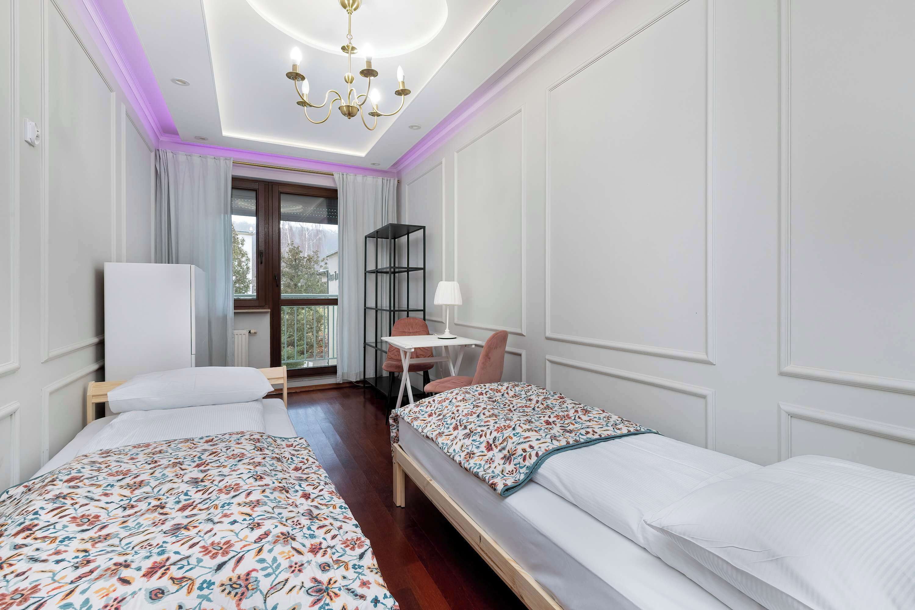 Een hotelkamer met twee bedden, een bureau, een stoel en een raam met gordijnen.
