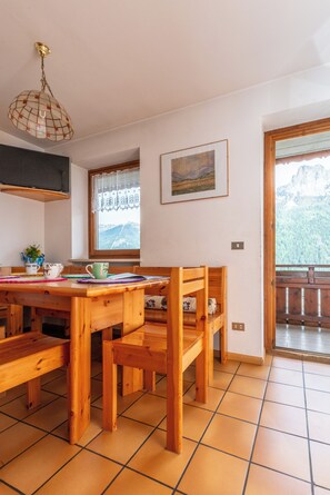 A wooden dining table with chairs, a window with a view of mountains, and a wooden bench. - Sports and nature in Trentino! (Vigo di Fassa)