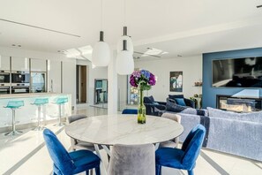 Ein modernes Wohnzimmer mit einem Marmortisch, blauen Stühlen und einem Sofa.