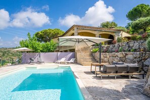 Ein Schwimmbecken mit Liegestühlen und einer überdachten Terrasse.