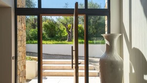 A modern interior with a large glass door leading to an outdoor area, a stone wall, and a large vase. - Villa spacieuse avec piscine (Opio)