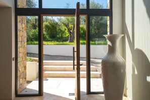 Ein modernes Interieur mit einer großen Glastür, die zu einem Außenbereich führt, einer Steinwand und einer übergroßen Vase.