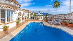 A pool area with a clear view of the sky, a stone wall, and a palm tree. - Villa with Private Pool, Garden, and Privacy in Cerros del Águila, Mijas (Mijas Costa)
