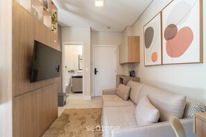 Ein modernes Wohnzimmer mit Flachbildfernseher, einer Couch und abstrakter Wandkunst.