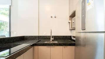 A modern kitchen with a stainless steel refrigerator, a built-in oven, and a black granite countertop.