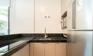 Eine moderne Küche mit einem Edelstahl-Kühlschrank, einem eingebauten Backofen und einer schwarzen Arbeitsplatte aus Granit.