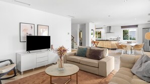 Un salon moderne avec un canapé, un téléviseur et un coin repas équipé de chaises.