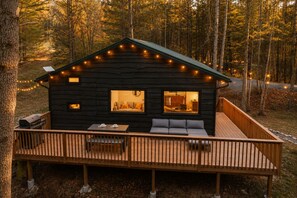A cabin with a deck, a grill, and a sofa.