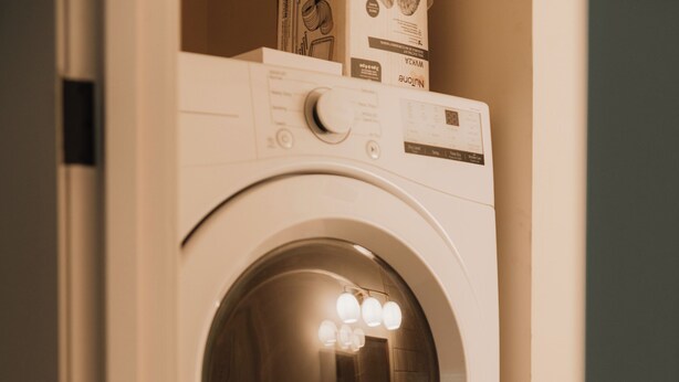 A stacked washer and dryer unit with control panels and a door. - Sauna, Hot Tub, Fire Pit & Creekside Deck | Niksen (Callicoon)