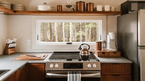 A kitchen with a stove, oven, and a window with a view of trees. - Sauna, Hot Tub, Fire Pit & Creekside Deck | Niksen (Callicoon)