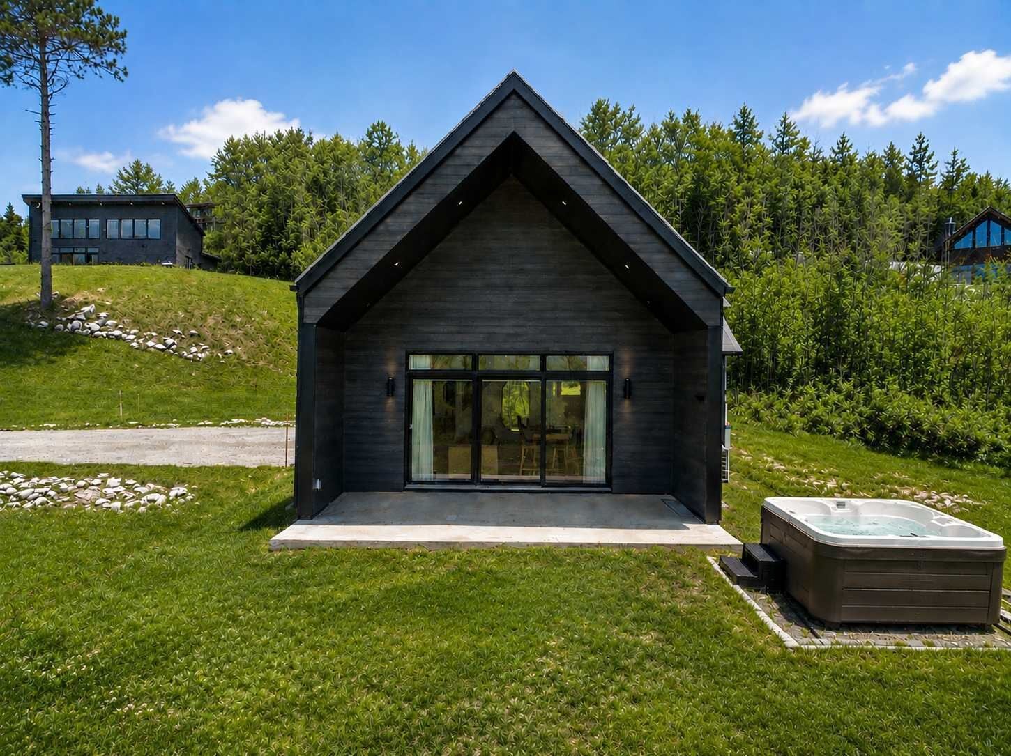 A modern house with a large glass door, a hot tub, and a well-maintained lawn.