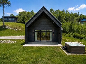 Ein modernes Haus mit großen Glasfenstern, einem Whirlpool und einem gepflegten Rasen.