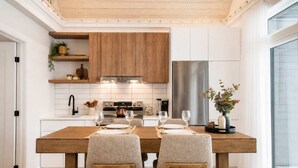 Una cucina moderna con mobili bianchi, un tavolo da pranzo in legno e un forno a incasso.
