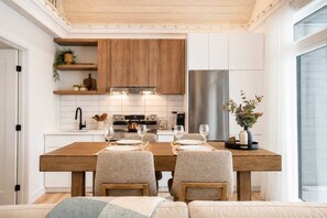 Eine moderne Küche mit weißen Schränken, einem Holztisch und einem eingebauten Backofen.